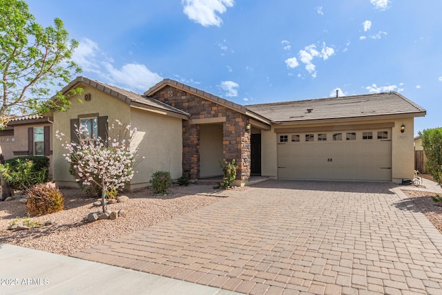 view of front of house featuring a garage, stone siding, a tile roof, decorative driveway, and stucco siding