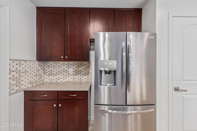 kitchen with light countertops, stainless steel refrigerator with ice dispenser, dark brown cabinetry, and decorative backsplash