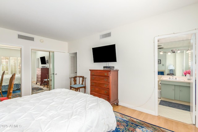bedroom featuring a sink, ensuite bath, visible vents, and wood finished floors