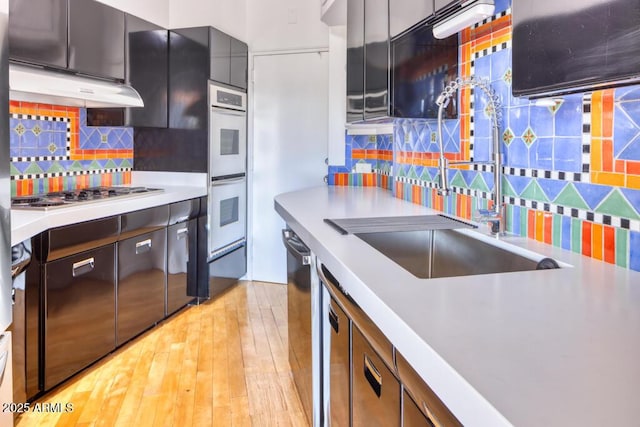 2201 N Central Ave Unit 3D, Phoenix, AZ 85004 - kitchen with stainless steel gas cooktop, decorative backsplash, double oven, under cabinet range hood, and light countertops