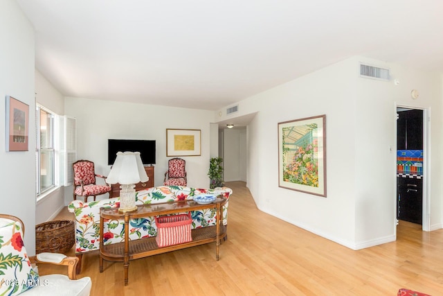 living area with light wood-style flooring, baseboards, and visible vents