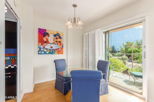 dining space with baseboards, an inviting chandelier, and wood finished floors
