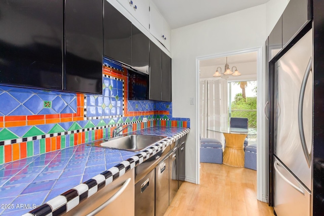 kitchen featuring a sink, freestanding refrigerator, tile counters, tasteful backsplash, and dark cabinetry