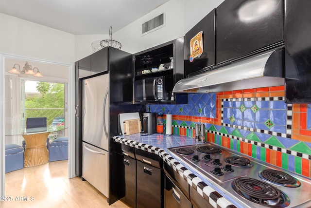 kitchen featuring under cabinet range hood, dark cabinetry, visible vents, backsplash, and appliances with stainless steel finishes