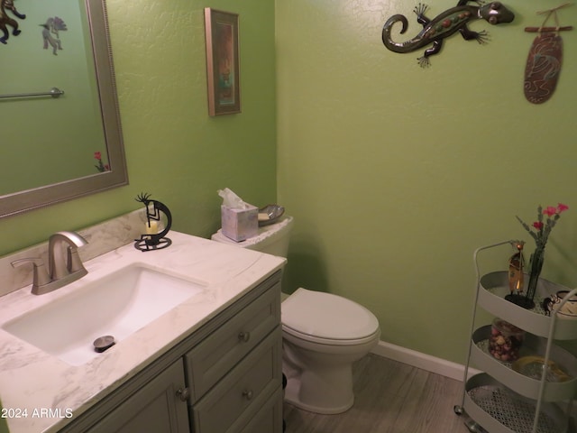 bathroom with wood-type flooring, toilet, and vanity