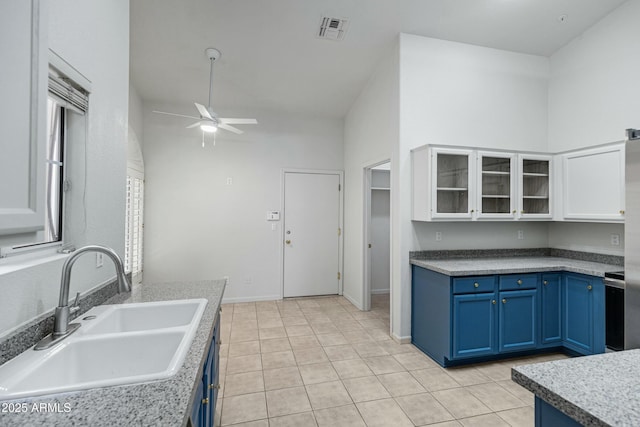 kitchen featuring blue cabinetry, visible vents, glass insert cabinets, white cabinetry, and a sink