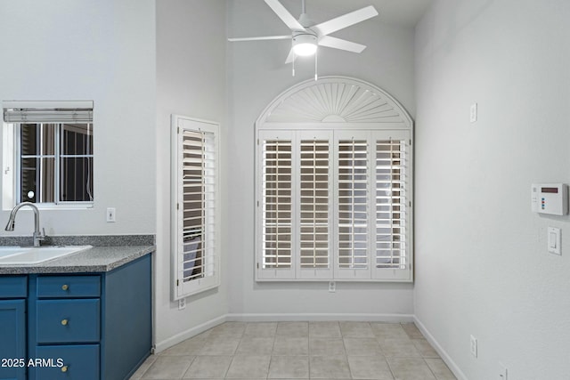 kitchen featuring ceiling fan, dark countertops, a sink, and baseboards