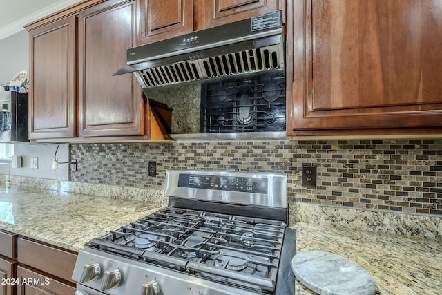 kitchen with gas stove, ventilation hood, light stone counters, and tasteful backsplash