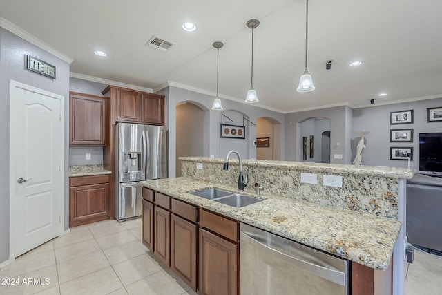 kitchen featuring stainless steel appliances, crown molding, sink, hanging light fixtures, and an island with sink