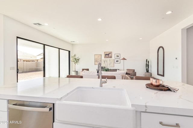 kitchen with sink, light stone countertops, white cabinets, and dishwasher