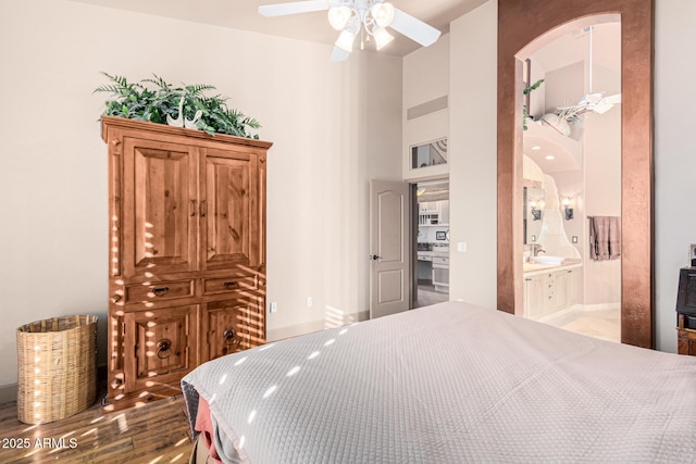 bedroom with sink, ensuite bath, ceiling fan, a towering ceiling, and light wood-type flooring