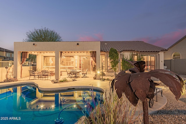 pool at dusk with a patio area