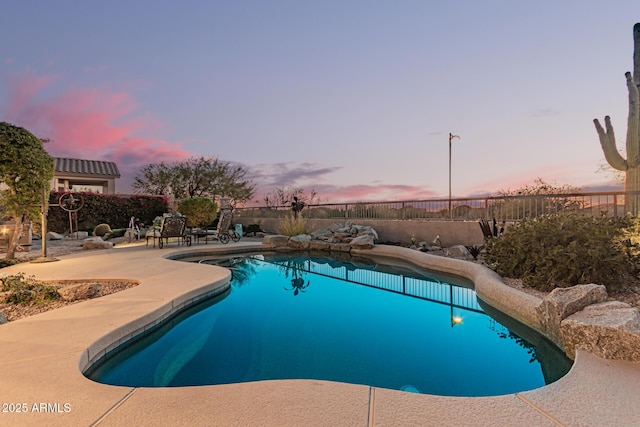 pool at dusk featuring a patio