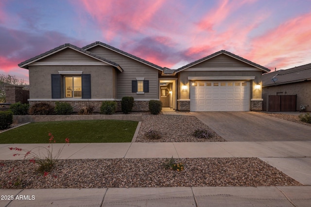 view of front of home with a garage, brick siding, decorative driveway, a front lawn, and stucco siding