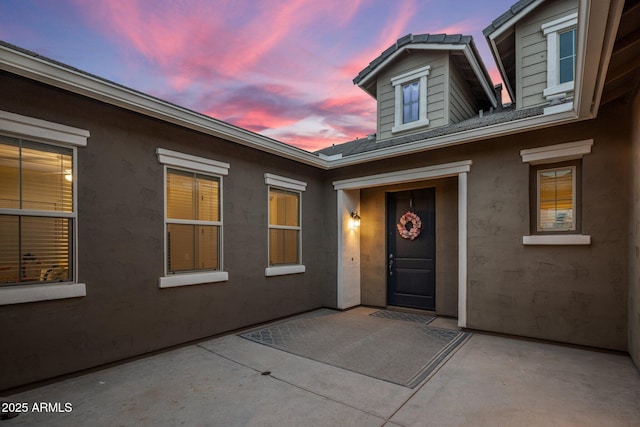 exterior entry at dusk featuring a patio and stucco siding