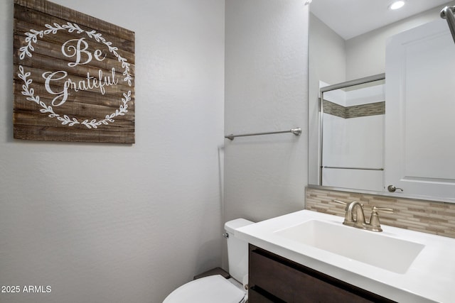 bathroom featuring tasteful backsplash, a shower with door, vanity, and toilet