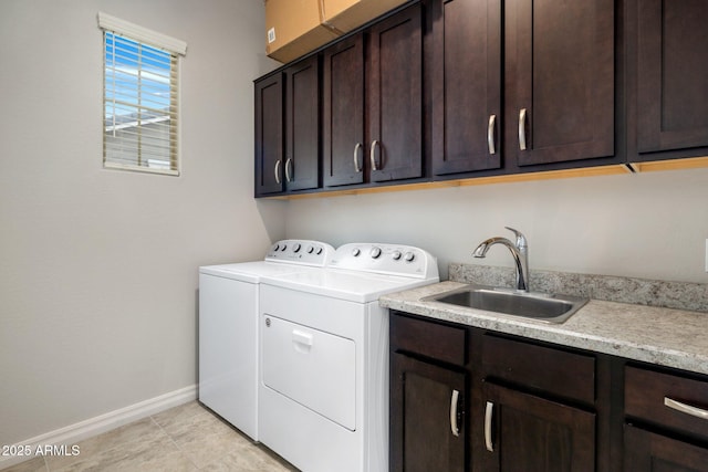 washroom featuring cabinet space, baseboards, independent washer and dryer, a sink, and light tile patterned flooring