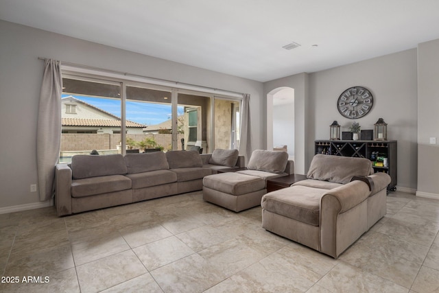 living area featuring baseboards, visible vents, and arched walkways