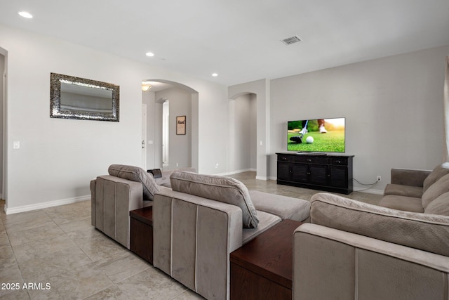 living room featuring arched walkways, baseboards, visible vents, and recessed lighting