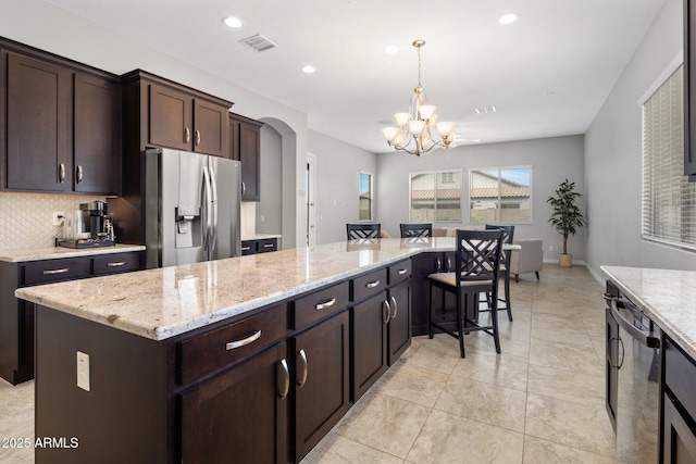 kitchen featuring arched walkways, visible vents, appliances with stainless steel finishes, a kitchen island, and dark brown cabinetry