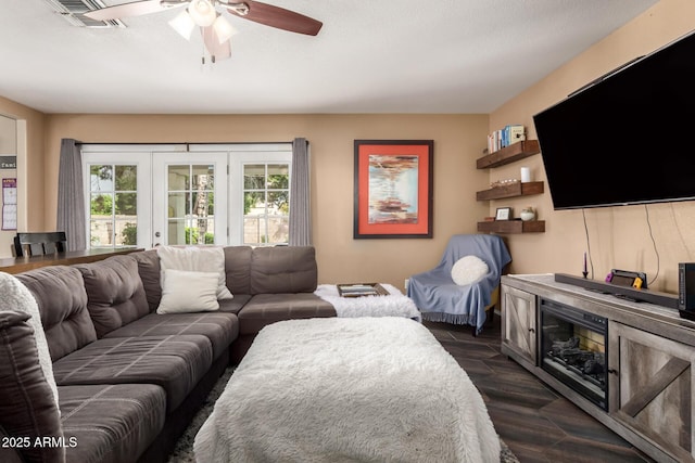 living area with dark wood finished floors, visible vents, a ceiling fan, and a healthy amount of sunlight