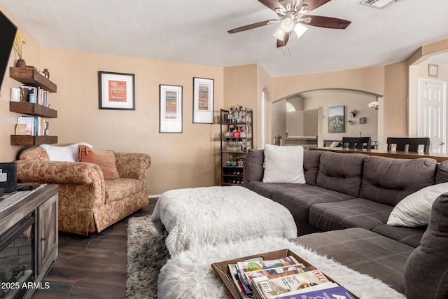living room with a ceiling fan, arched walkways, and visible vents