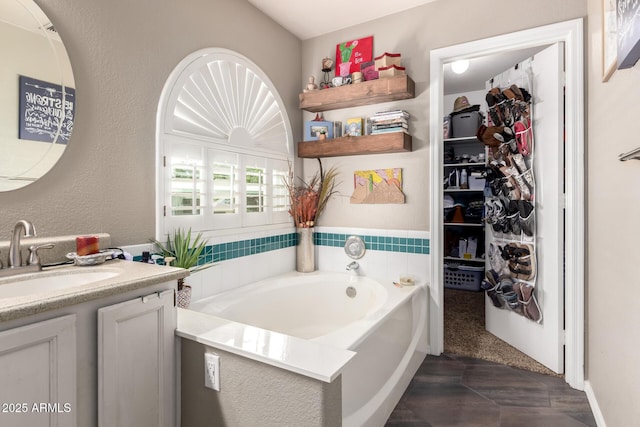 bathroom featuring a textured wall, a garden tub, and vanity