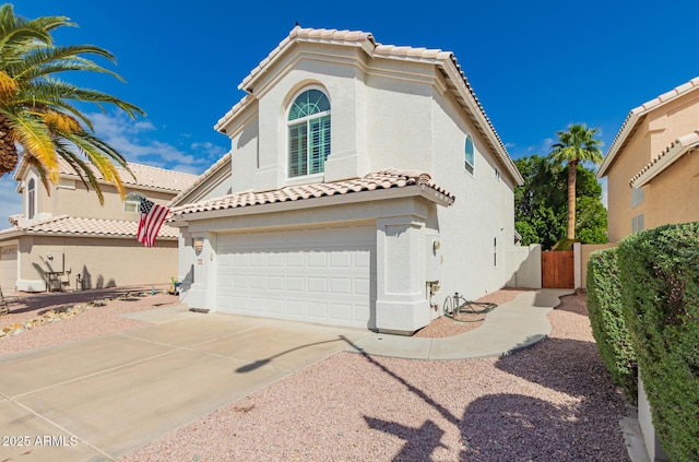 mediterranean / spanish-style house featuring a tile roof, stucco siding, an attached garage, and driveway
