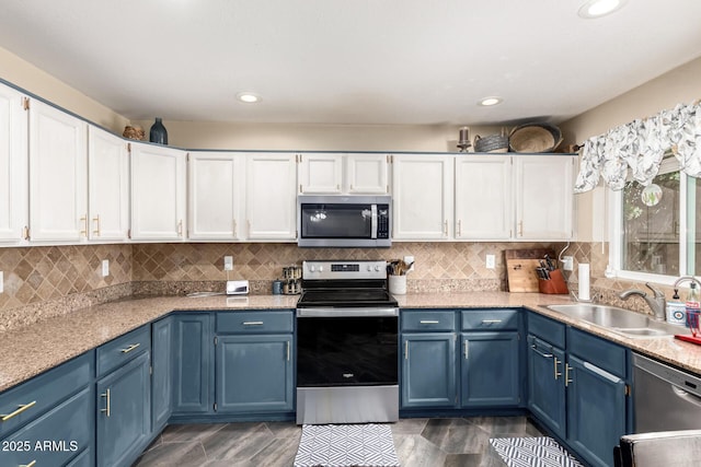 kitchen with a sink, white cabinetry, tasteful backsplash, appliances with stainless steel finishes, and blue cabinetry