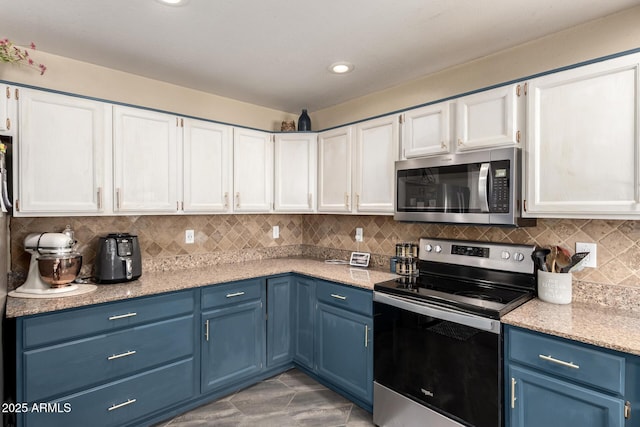 kitchen with white cabinetry, blue cabinetry, stainless steel appliances, and backsplash