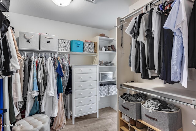 walk in closet with light hardwood / wood-style flooring