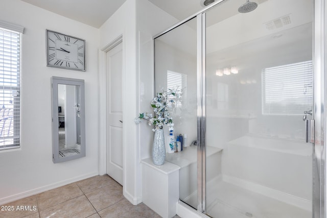 bathroom featuring tile patterned flooring, a wealth of natural light, and a shower with shower door