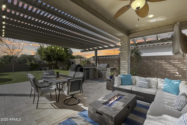 patio terrace at dusk with an outdoor kitchen, a pergola, area for grilling, and an outdoor living space with a fire pit