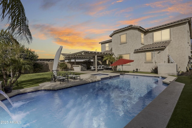 pool at dusk featuring a pergola, a patio area, a lawn, and an in ground hot tub