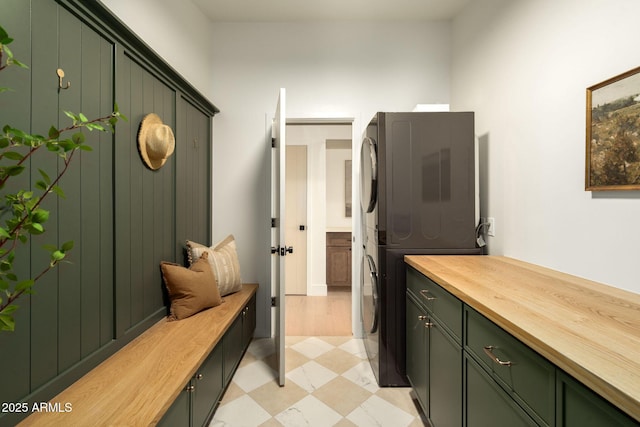 mudroom featuring light floors and stacked washer and dryer