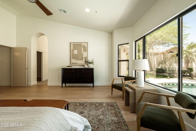 bedroom featuring high vaulted ceiling, visible vents, baseboards, arched walkways, and wood finished floors
