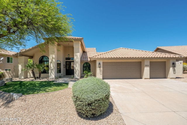 mediterranean / spanish-style house featuring a tiled roof, stucco siding, concrete driveway, and an attached garage