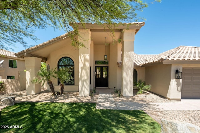 view of front of home with stucco siding, a tiled roof, a front yard, and a garage