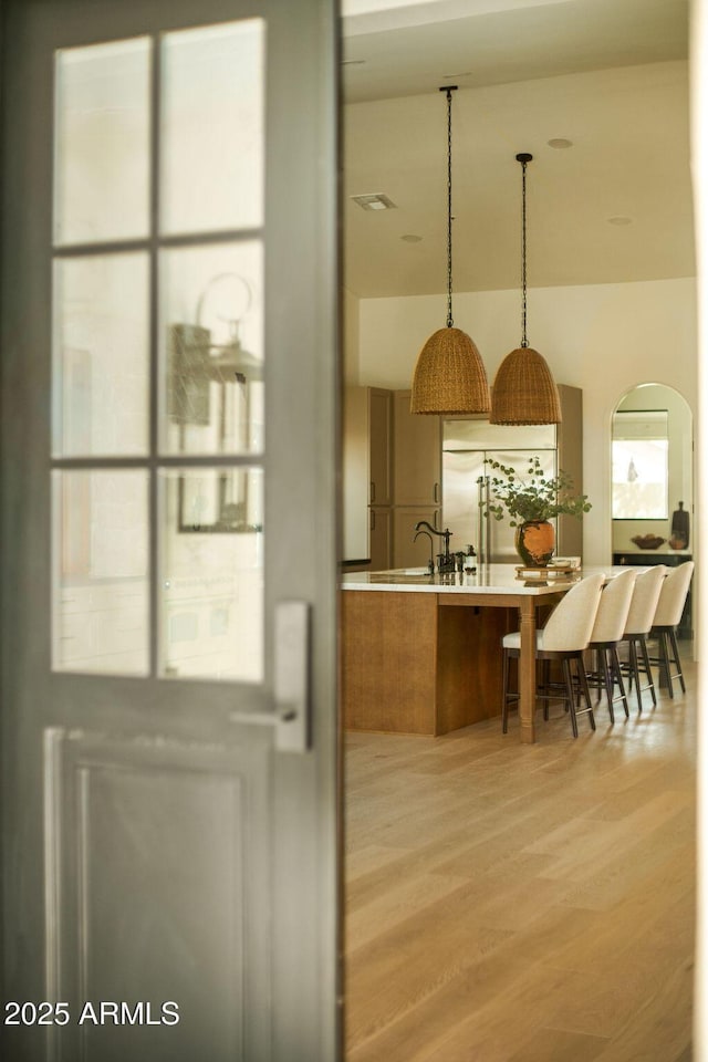 kitchen featuring a breakfast bar area, pendant lighting, light wood-style floors, and a sink