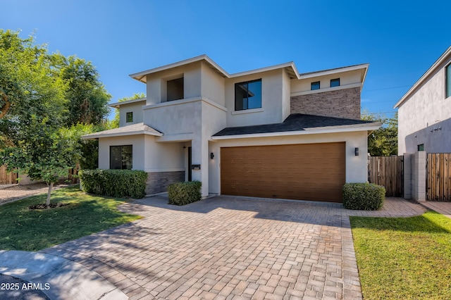 view of front of home featuring fence, stucco siding, an attached garage, and decorative driveway