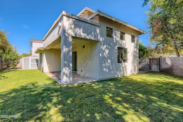 rear view of property with a storage shed, a fenced backyard, a gate, an outbuilding, and a patio