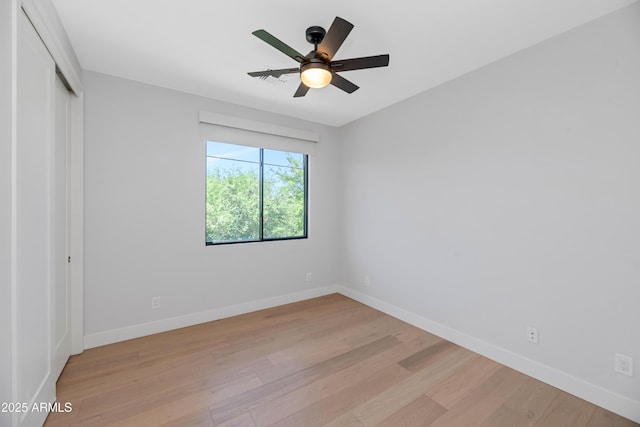 unfurnished bedroom featuring baseboards, light wood-style flooring, ceiling fan, and a closet