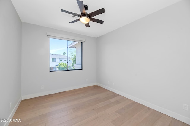 spare room with baseboards, ceiling fan, and light wood finished floors