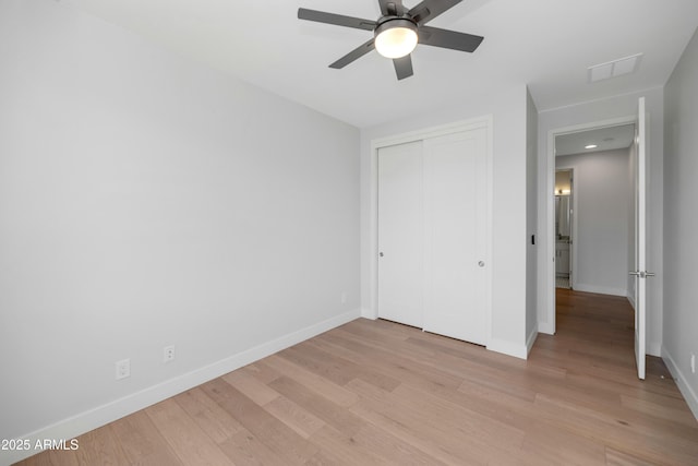 unfurnished bedroom with a closet, baseboards, visible vents, and light wood-type flooring