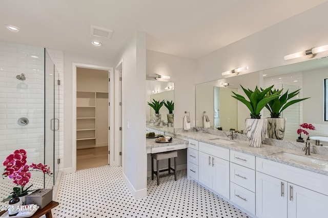 bathroom with double vanity, a sink, a walk in closet, and a shower stall