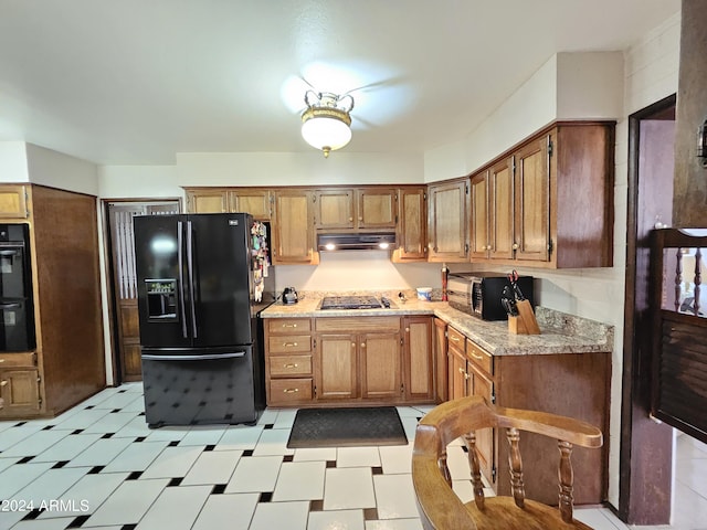 2201 E 7th St, Douglas, AZ 85607 - kitchen with black appliances, under cabinet range hood, light countertops, light flooring, and brown cabinets