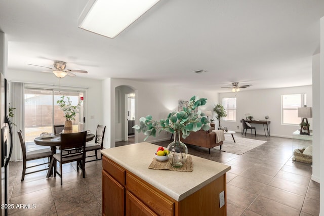 6515 W Hughes Dr, Phoenix, AZ 85043 - kitchen featuring ceiling fan, arched walkways, a kitchen island, dark tile patterned flooring, and light countertops