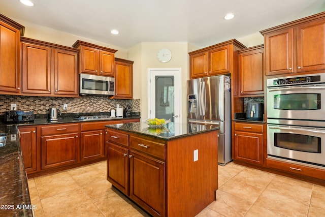 kitchen with a center island, decorative backsplash, stainless steel appliances, and dark stone countertops