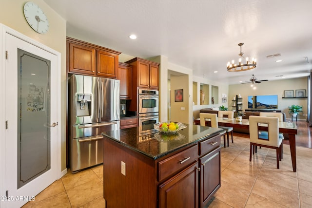kitchen with light tile patterned flooring, a center island, dark stone counters, stainless steel appliances, and visible vents