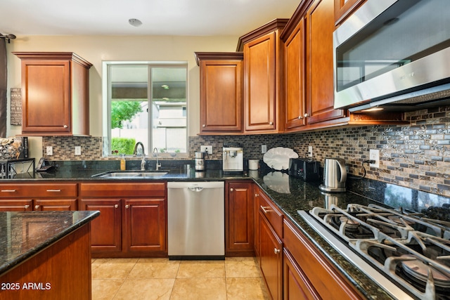 kitchen featuring a sink, dark stone countertops, backsplash, light tile patterned floors, and stainless steel appliances